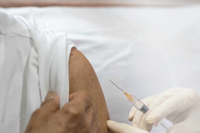 Senior vaccination concept. Elderly getting immune vaccine at arm for flu shot, pneumonia, and shingles(MMR) in hospital by nurse. Doctor giving an injection to older people patient in clinic.